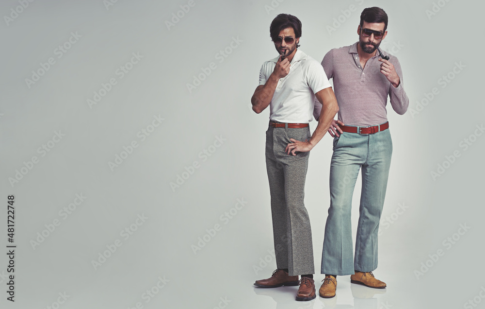 Theyve变得很时尚。两个男人站在一起，穿着复古的70年代服装和