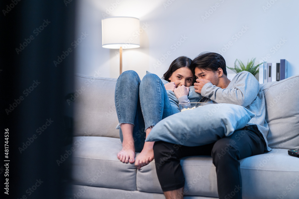 亚洲年轻情侣在家里的客厅里一起看电影。
