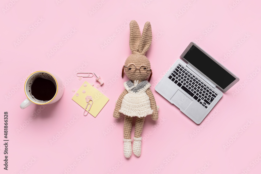 彩色背景上有兔子玩具、咖啡杯和文具的微型笔记本电脑