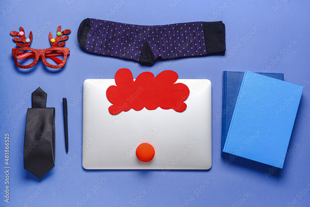Laptop with party decor, necktie and socks on color background
