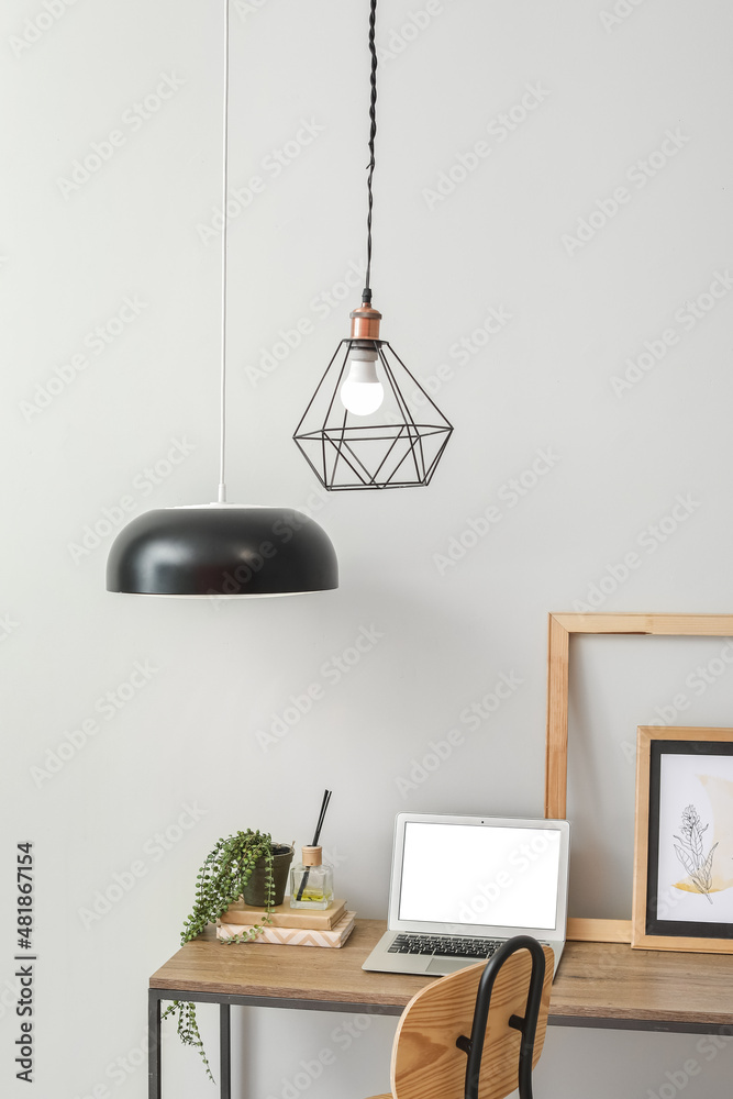 Stylish workplace with hanging pendant lamps in light room