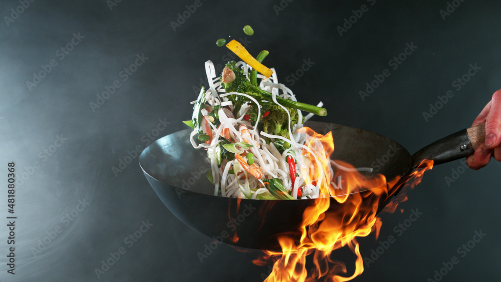 厨师把大虾从锅里扔进火里的特写镜头。