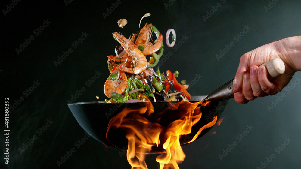 厨师把大虾从锅里扔进火里的特写镜头。