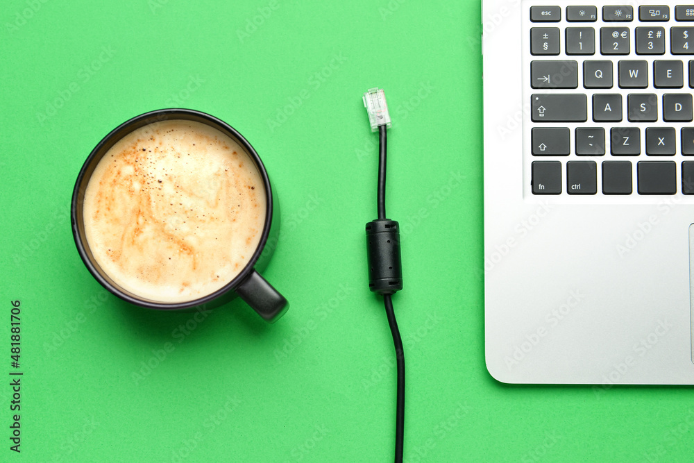 绿色背景下的一杯咖啡、网线和笔记本电脑