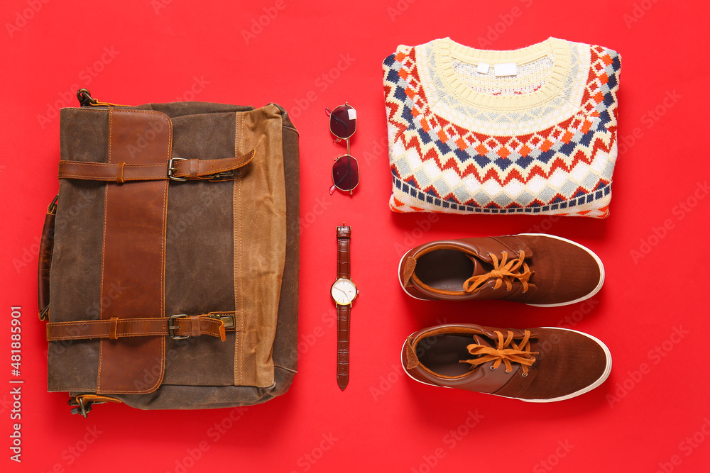 Male sweater, shoes, bag, sunglasses and wristwatch on red background