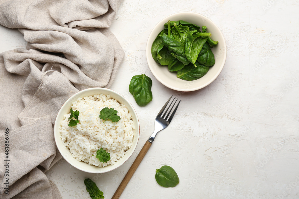 Bowl with tasty boiled rice and spinach on light background