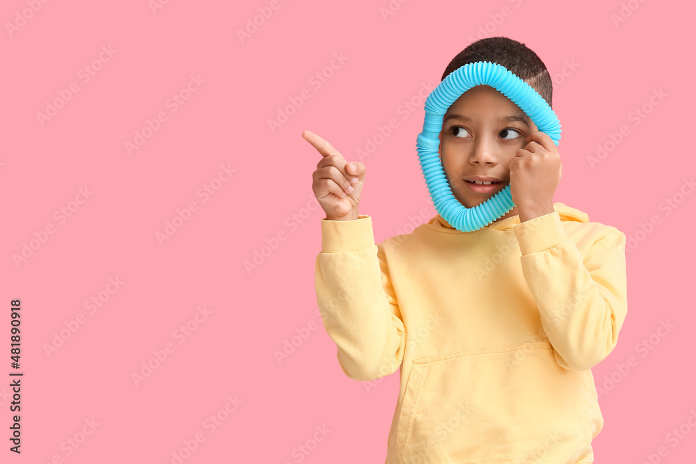 一个非洲裔美国小男孩，拿着蓝色的Pop Tube指着粉色背景上的东西