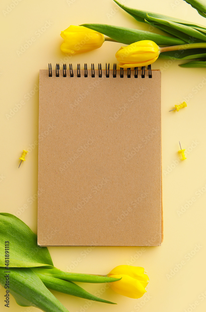 用空白笔记本和彩色背景上的黄色郁金香创作