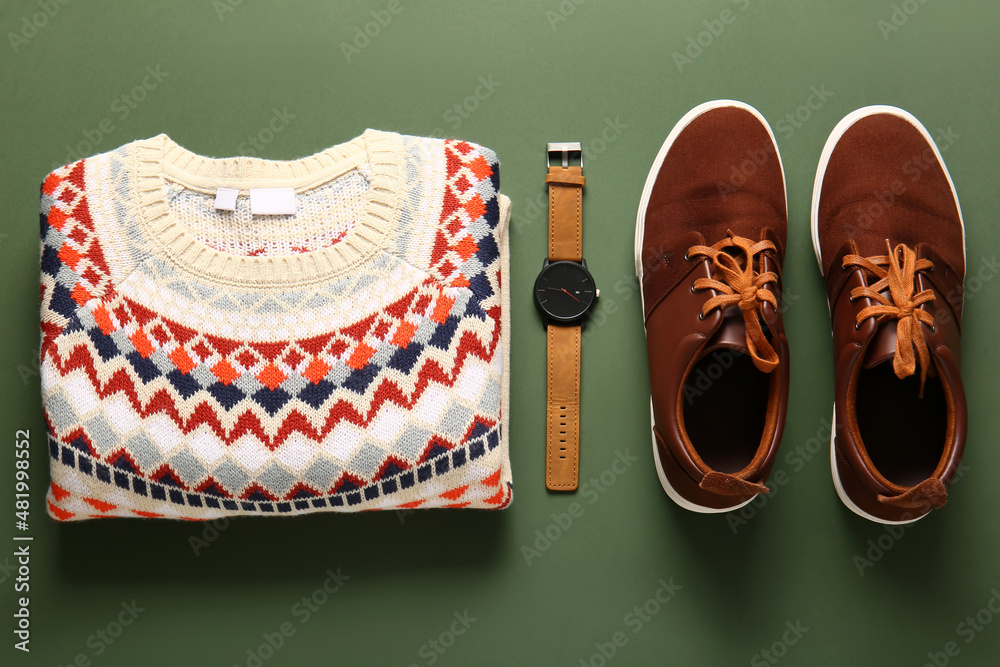 Male sweater, wristwatch and shoes on green background