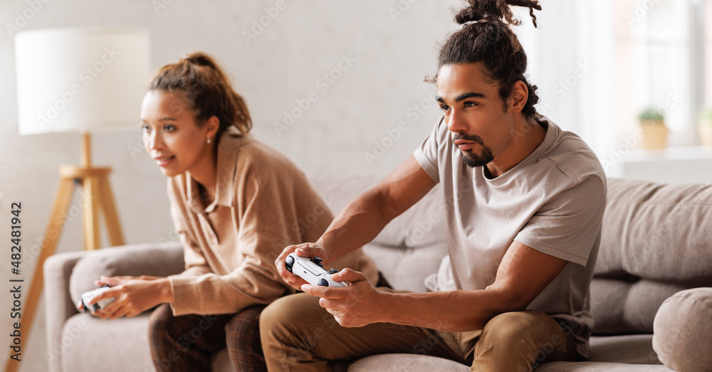 African american couple laugh and play video games together using a video game console