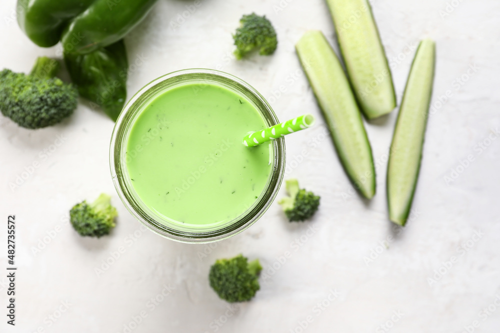 Glass of healthy green juice on light background