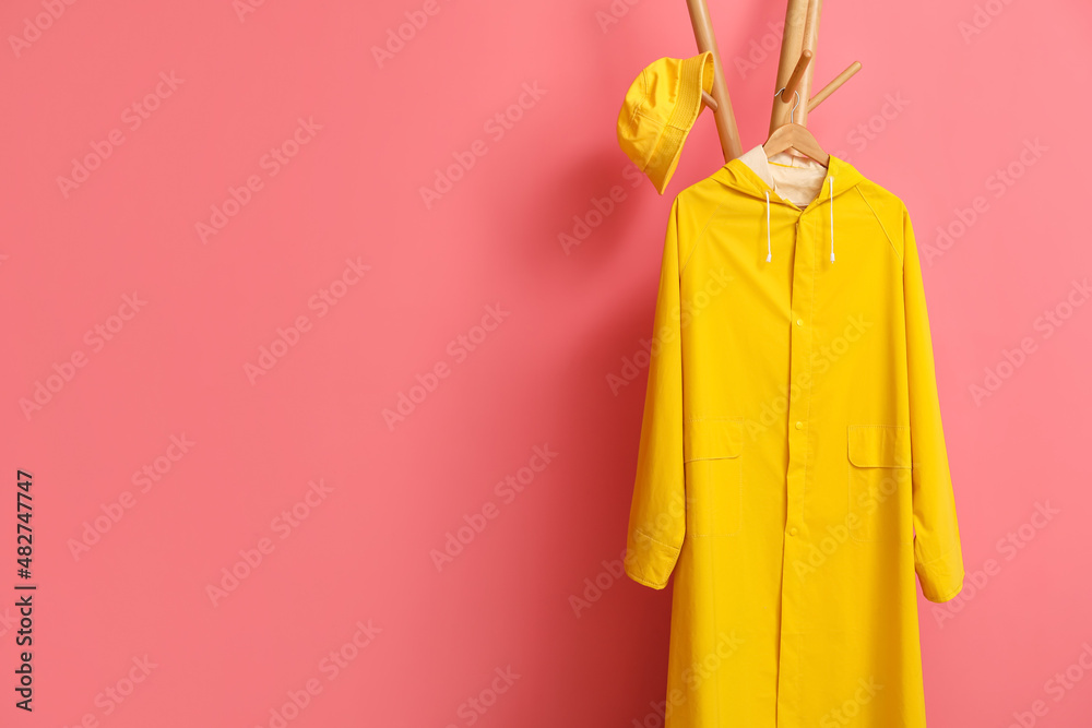 粉色墙壁附近带黄色雨衣和帽子的架子