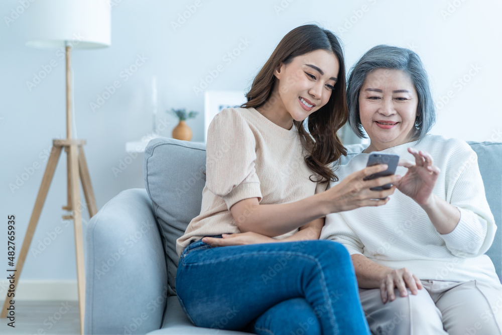 亚洲可爱的家庭，年幼的女儿和年长的母亲一起使用手机