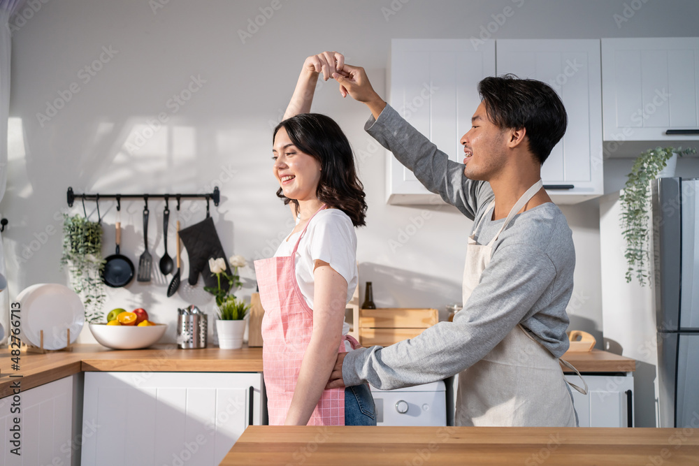 亚洲迷人的情侣在家里的厨房里一起跳舞