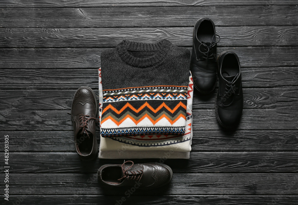 深色木质背景上的一堆男性毛衣和鞋子