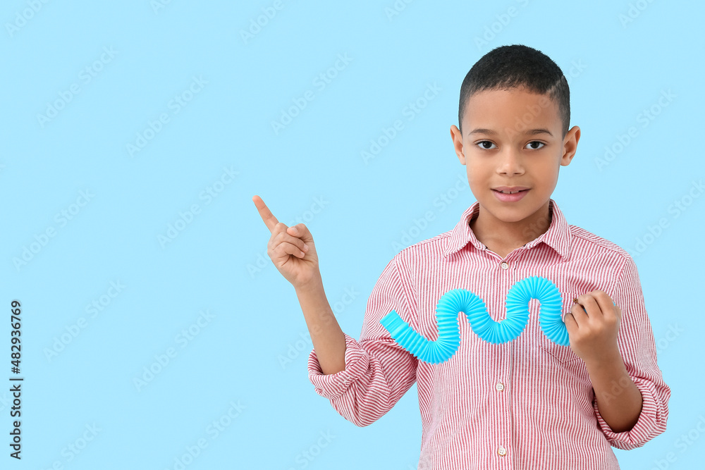 带着Pop-Tube的非裔美国小男孩指着蓝色背景上的东西