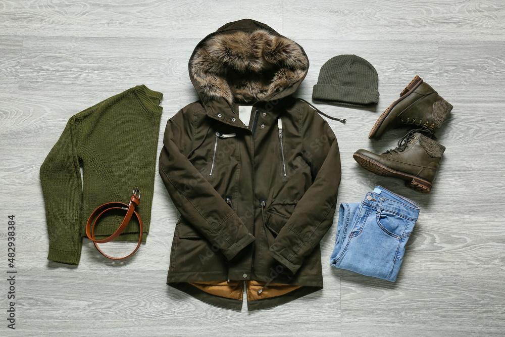 灰色木质背景的夹克、裤子、毛衣、帽子、鞋子和腰带