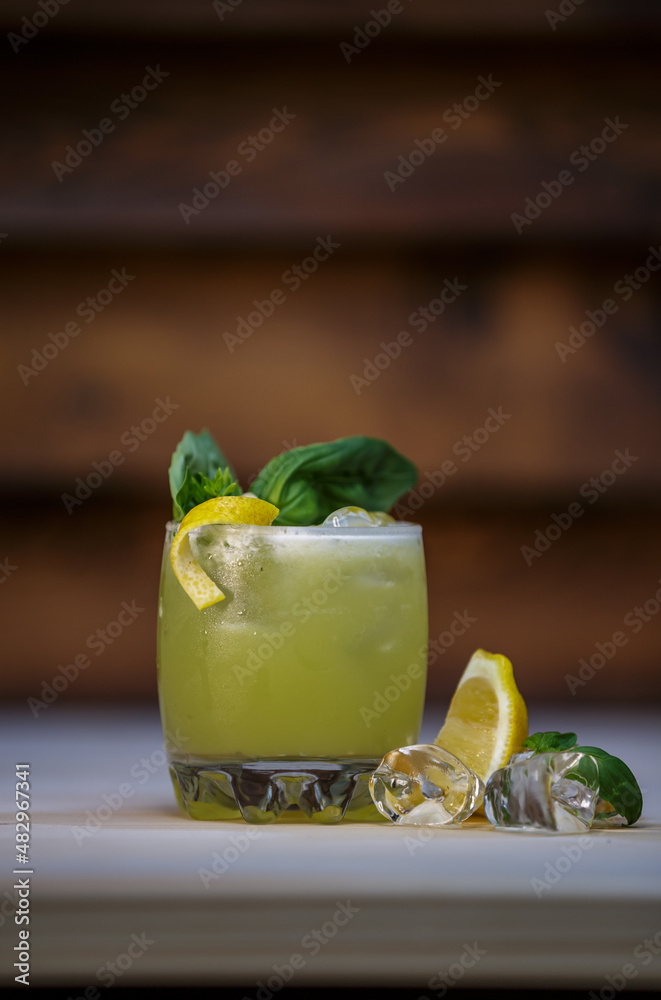 Fresh cold lime smoothie cocktail with mint and crushed ice and lemon twist to garnish on table with