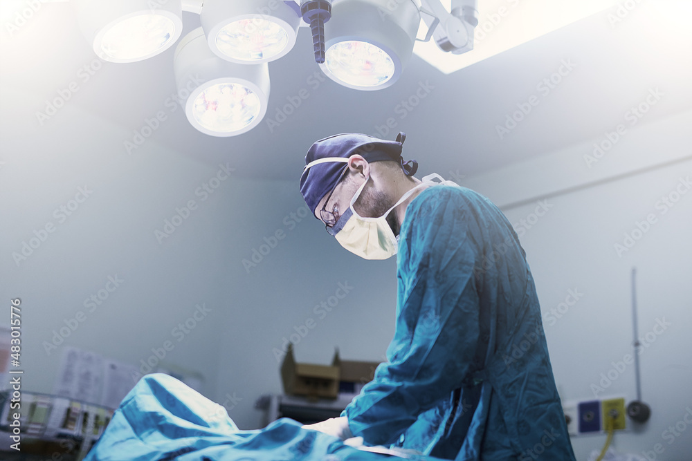 小心。一位专注的年轻外科医生在手术室为患者做手术的镜头