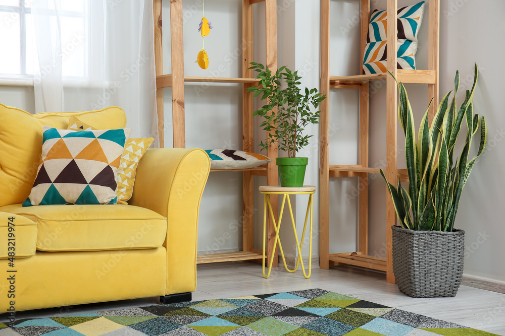 Comfortable sofa, shelf units and houseplants in living room interior