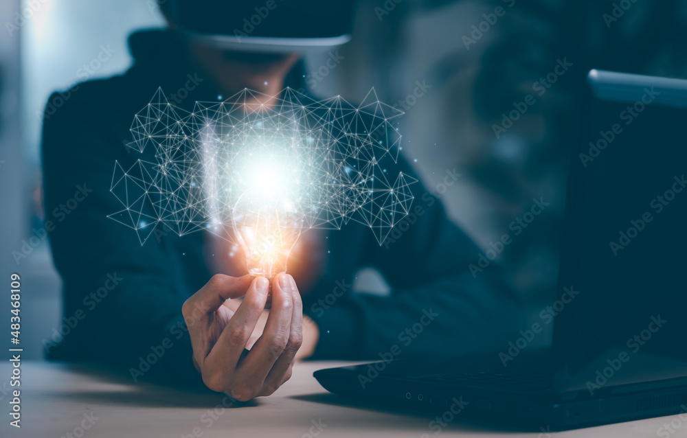 Man wearing VR glasses virtual and holding light bulb with icons and working on the desk, Creativity