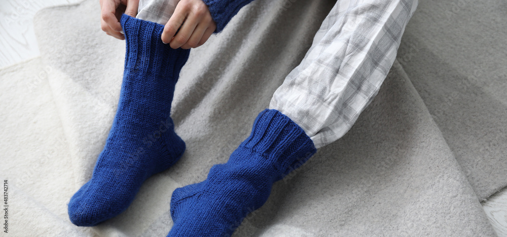 女人在家穿上保暖的针织袜子。供暖季节的概念