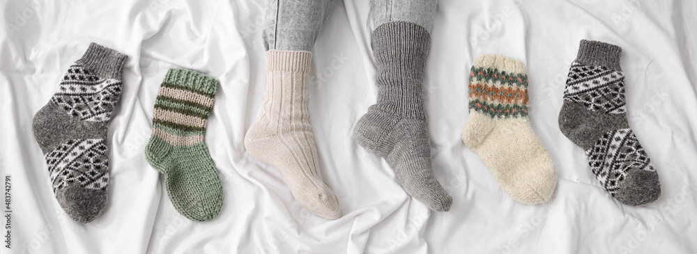床上穿着不同保暖袜子的女性腿，俯视图。供暖季节的概念