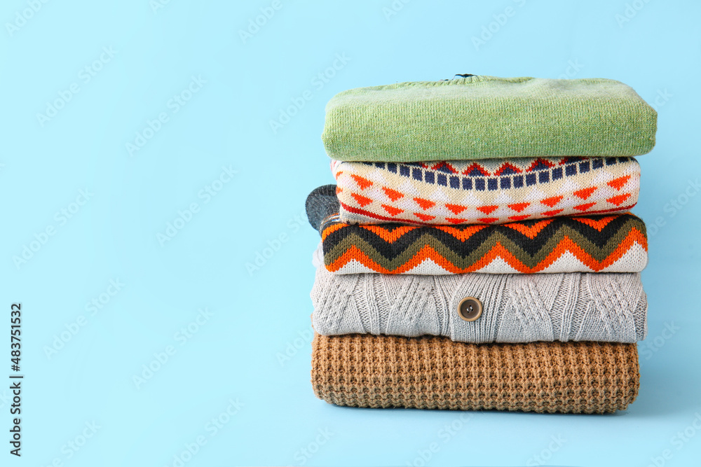 Stack of different sweaters on blue background
