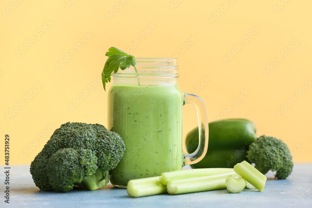 Mason jar of healthy green juice and fresh ingredients on table
