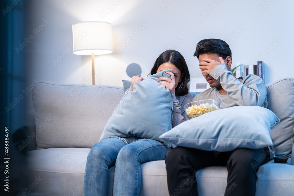 Asian young funny couple watch jump scare movie on television at home. 