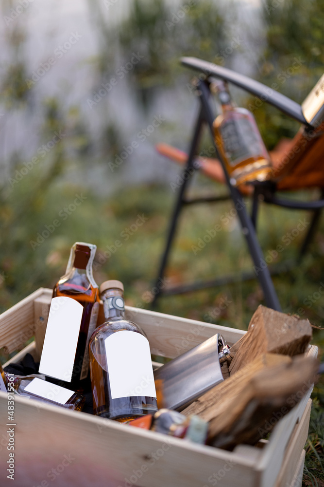 野餐或钓鱼时，木箱和折叠椅上放有烈性酒精的瓶子。带空白的瓶子