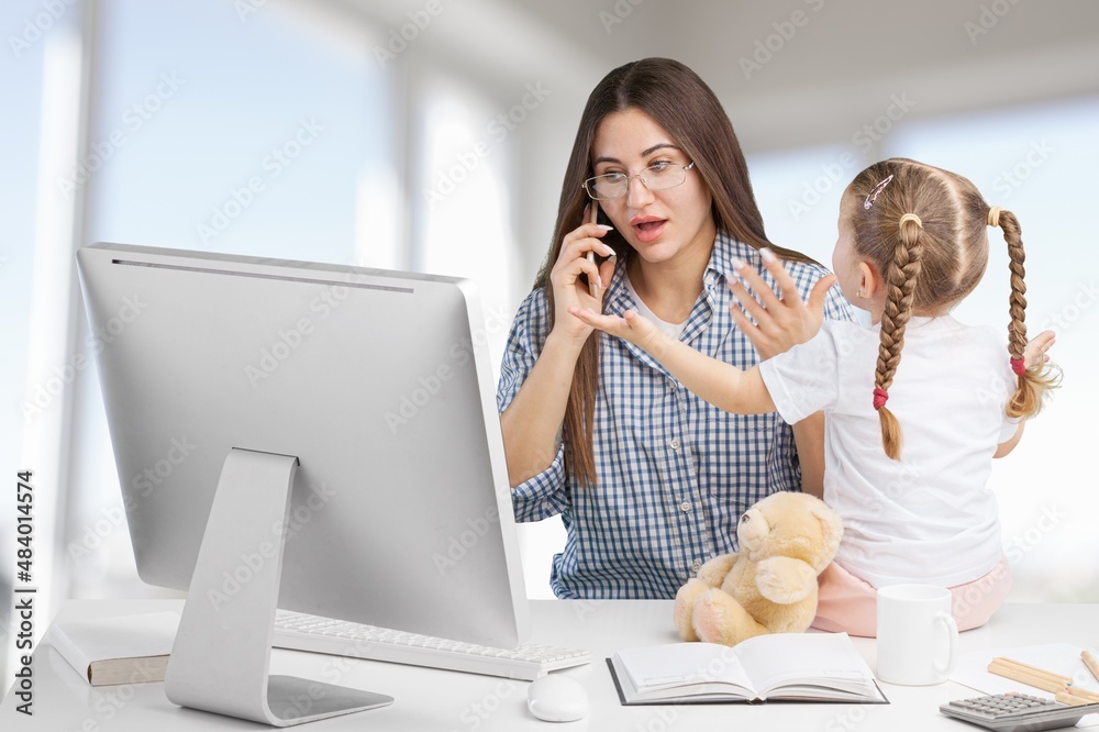 Beautiful young mother working for computer it home with little spoiled child . Mom or teacher and l