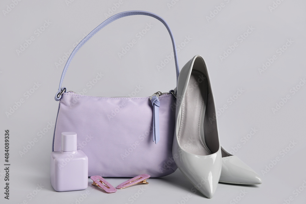 Stylish handbag, shoes, perfume and hair clips on light background