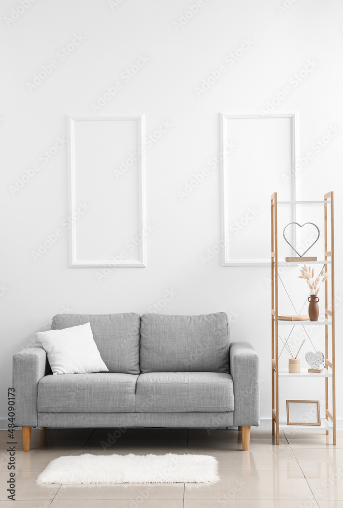 Comfy grey couch with shelving unit near white wall