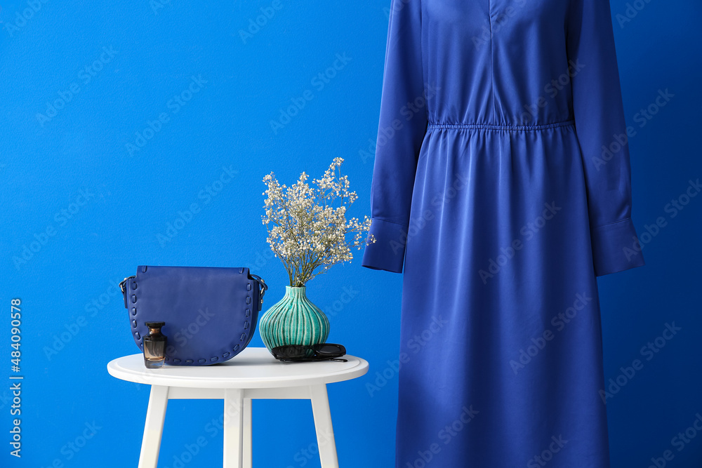 Table with female accessories and elegant dress near color wall