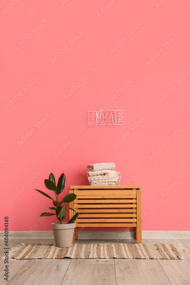 木桌上放着儿童毛衣的篮子，室内植物，室内彩色墙上写着家
