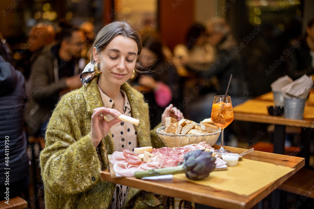 女人吃意大利肉开胃菜，各种肉片和奶酪配面包和Aperol雪碧