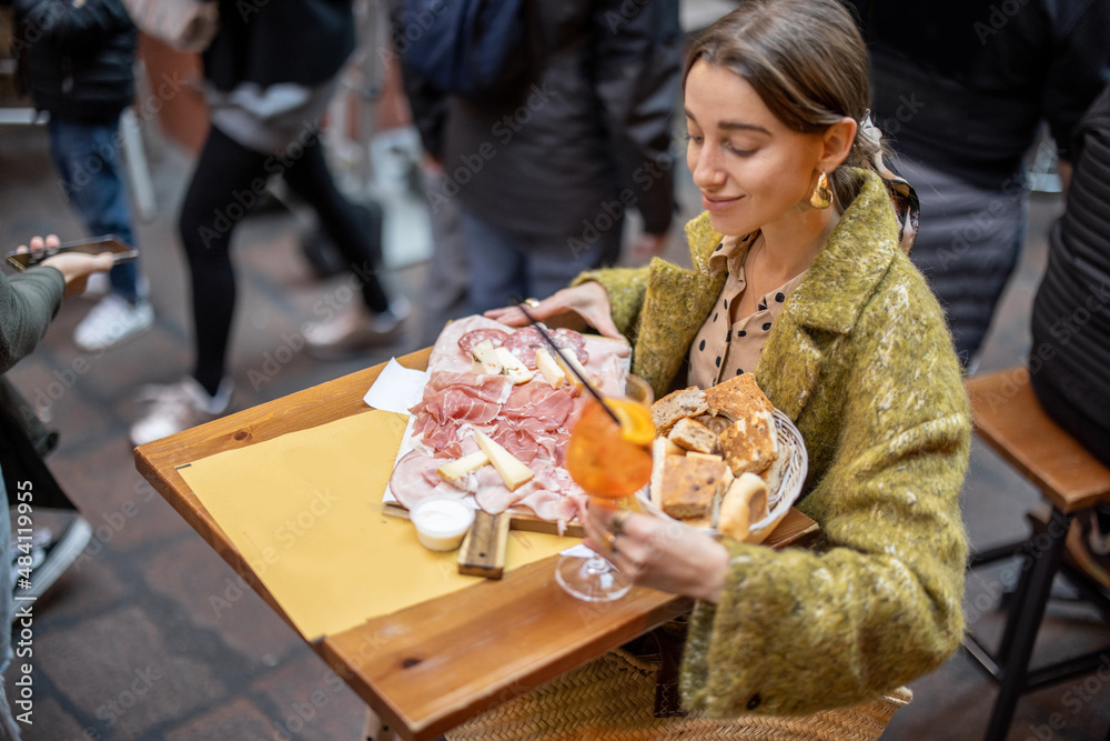 女人在餐厅吃意大利肉类开胃菜、各种肉片和奶酪配面包和Aperol雪碧