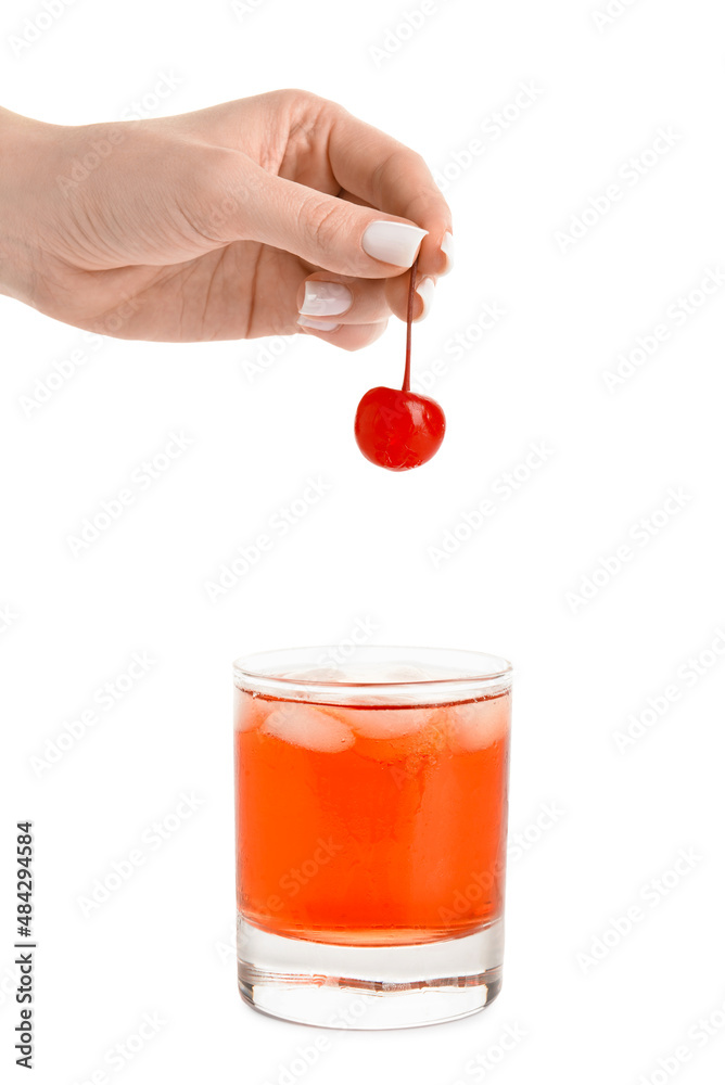 一个女人在曼哈顿鸡尾酒的白底玻璃杯里放樱桃