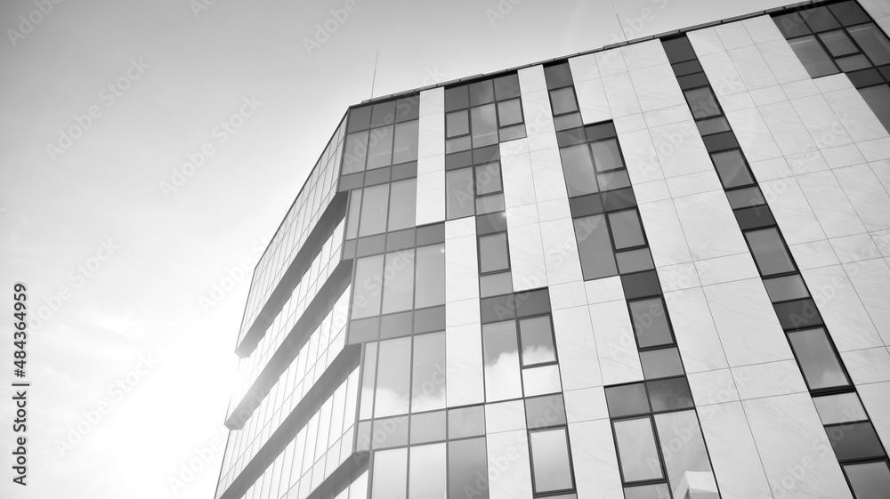 户外办公楼的现代玻璃和铝墙，阳光明媚。黑色和白色