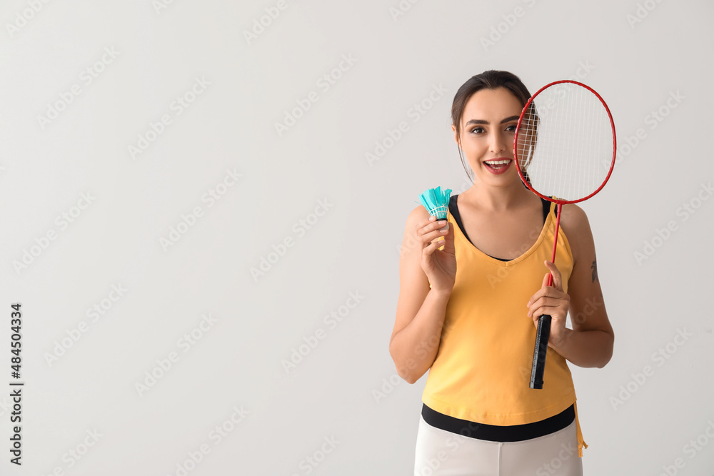Sporty female badminton player on light background