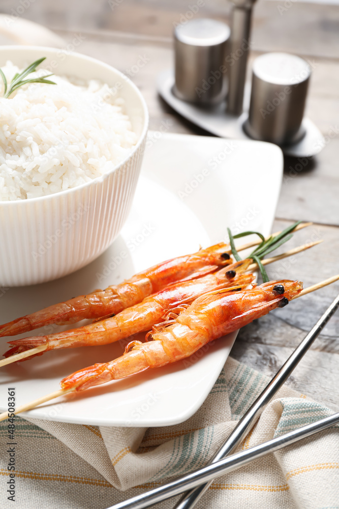 Plate with tasty grilled shrimp skewers and rice on wooden background