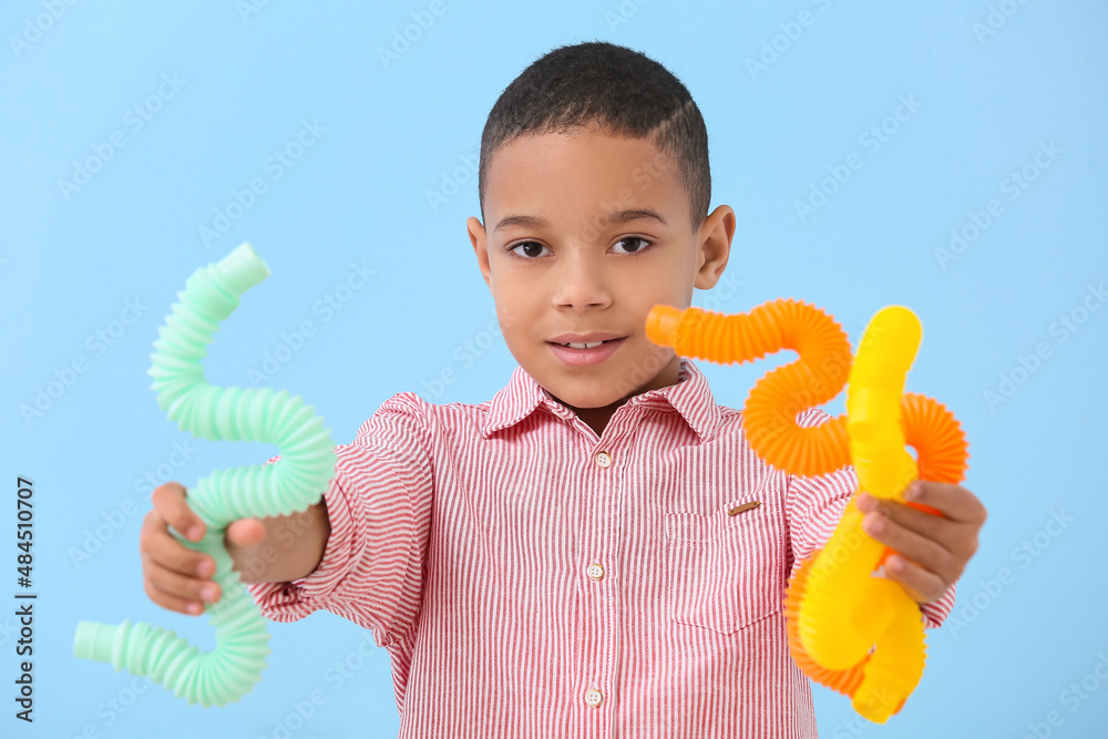 Little African-American boy with Pop Tubes on blue background
