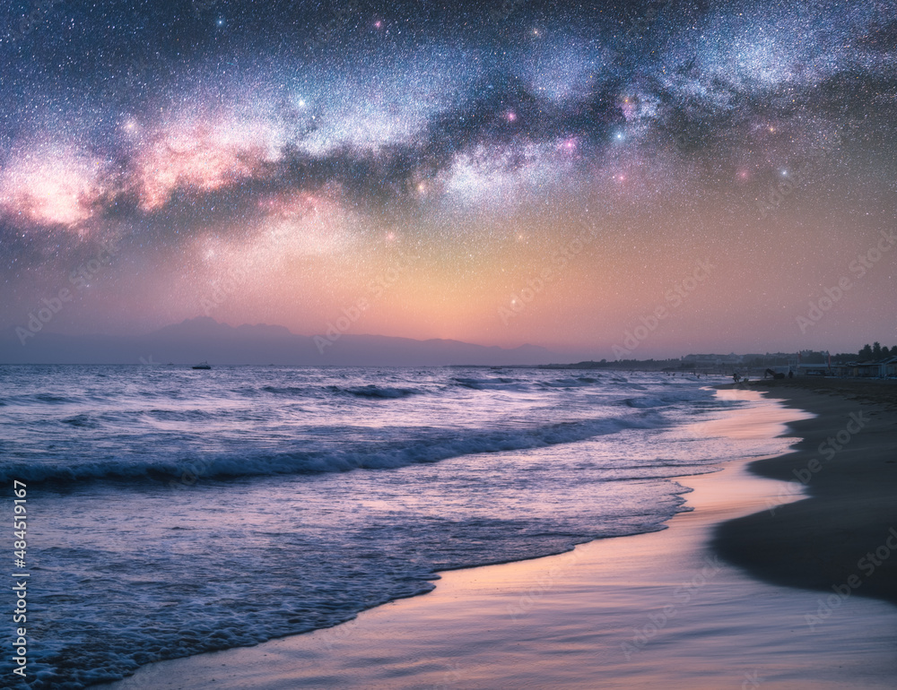 夏季夜晚，蓝色的大海和沙滩上有银河。美丽的星空与银河和