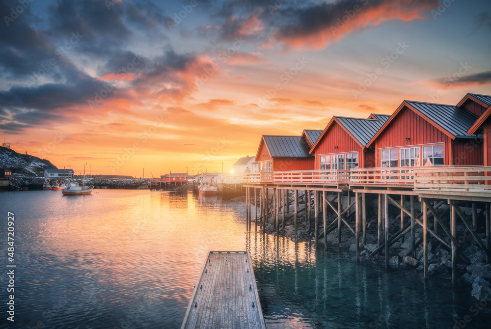 海边木桩上的红色罗布，小码头，冬天日出时五颜六色的橙色天空。罗弗特