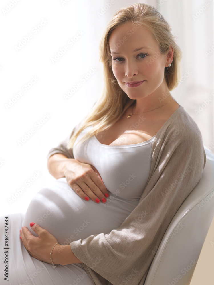 这真是一件幸事。一位迷人的年轻孕妇抱着肚子的剪短肖像