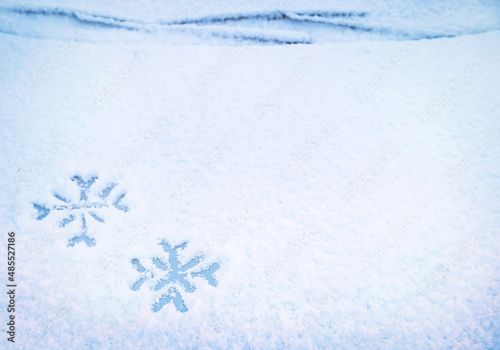 汽车挡风玻璃雨刮器下的雪地上手绘两片雪花。运输，冬天，天气