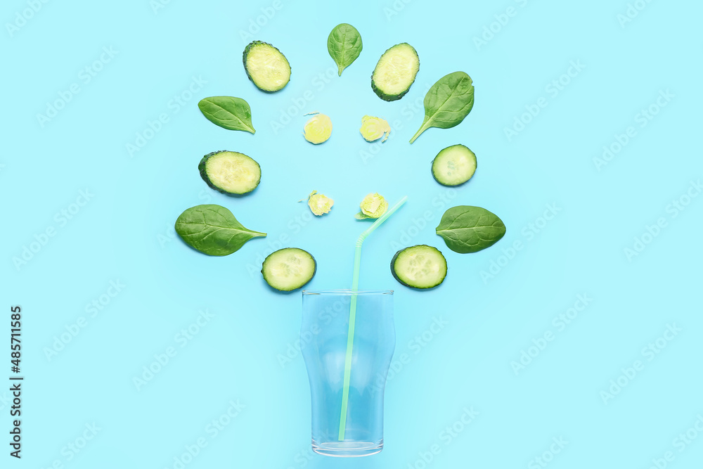 Composition with green vegetables and empty glass on blue background