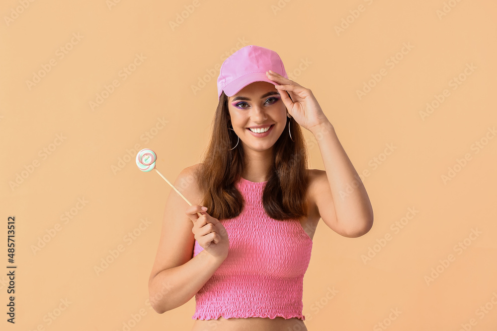 戴粉色帽子的漂亮年轻女子，米色背景是甜棒棒糖