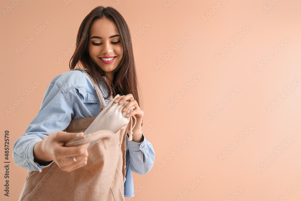 米色背景下带环保袋的年轻女性